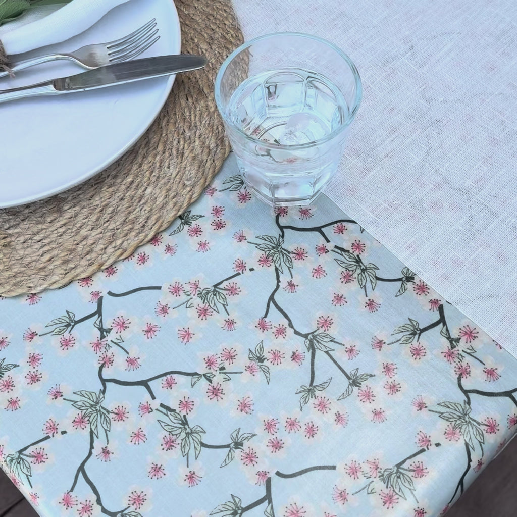 blue floral oilcloth on an outdoor table with a glass of water being spilled then wiped up easily