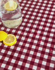 gingham red check tablecloth with water droplets sitting on top and a glass carafe with slices of lemon